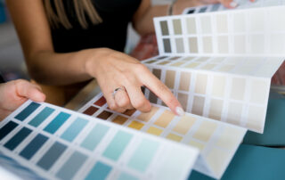 Close-up of two women choosing samples of wall paint. Interior designer consulting a client looking at a color swatch, color trends for home painting