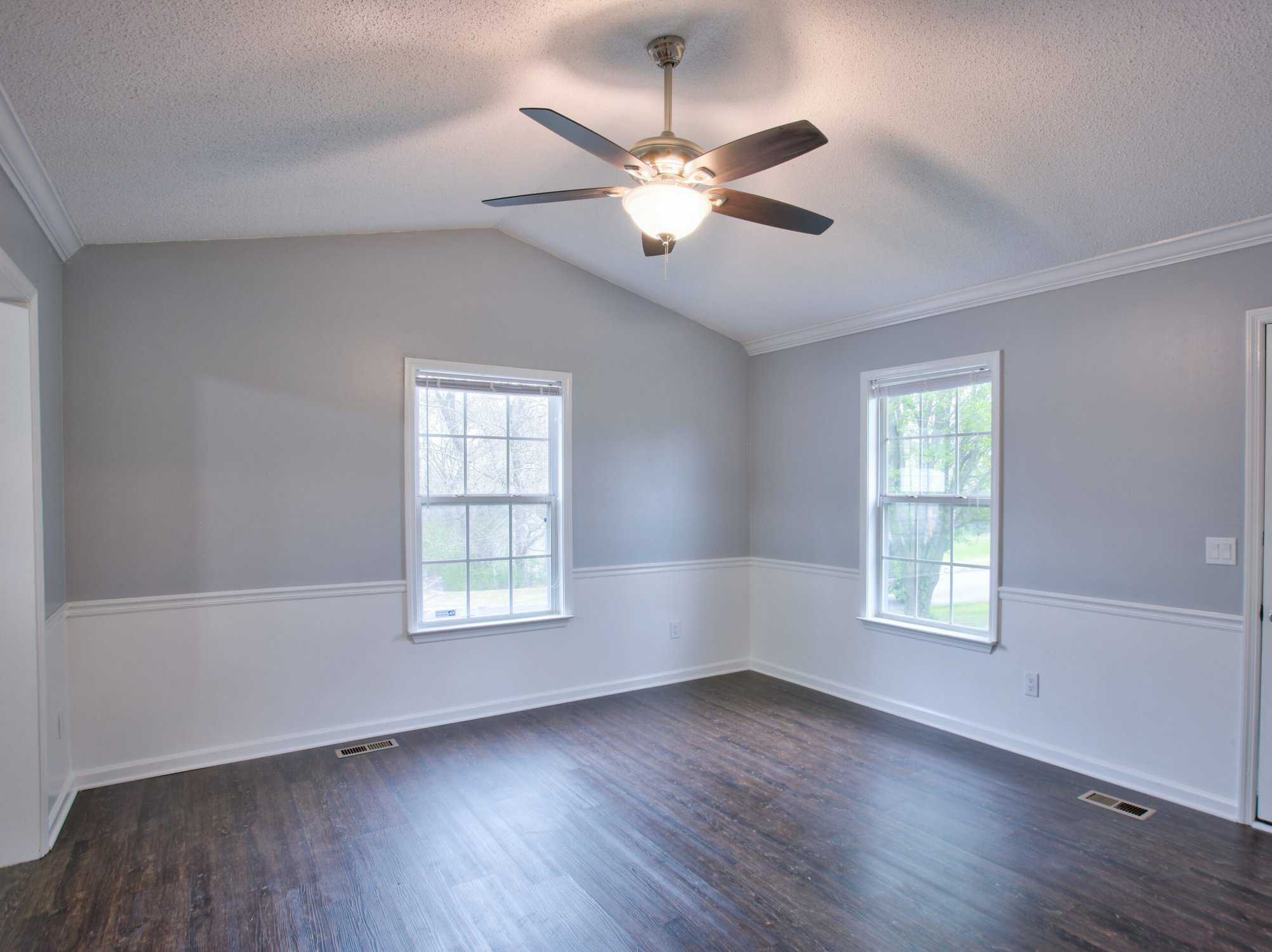 Gray living room interior with vaulted ceilings and chair rail, preparing walls for painting in cooler temperatures